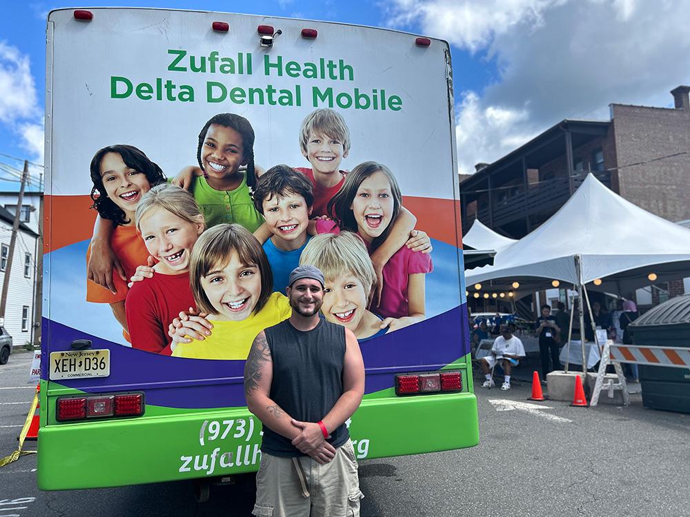 Person standing in front of mobile dental van smiling
