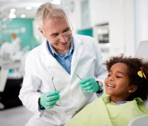 Male dentist with smiling child patient