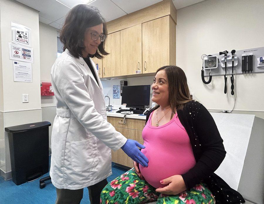 A doctor and pregnant patient are talking to one another during a prenatal visit.